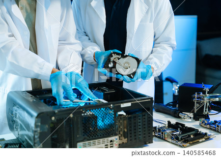 Technicians repairing hard drive and computer hardware in technology lab, focusing on data recovery, diagnostics, and electronic maintenance Technicians repairing hard drive and computer hardware in technology lab, focusing on data recovery, diagnostics, and electronic maintenance 140585468