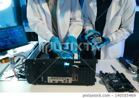 Engineers repairing computer hardware and hard drive in a technology lab. Concept of data storage, cybersecurity, digital infrastructure, electronics maintenance Engineers repairing computer hardware and hard drive in a technology lab. Concept of data storage, cybersecurity, digital infrastructure, electronics maintenance 140585469