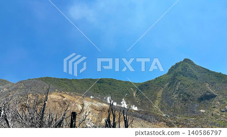 箱根大湧谷的山坡上,白色的煙霧在藍天下升騰,樹木光禿禿的。 箱根大湧谷的山坡上,白色的煙霧在藍天下升騰,樹木光禿禿的。 140586797