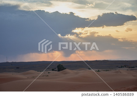 The setting sun disappears behind the majestic sand dunes of the Merzouga desert at sunset in Morocco 140586889