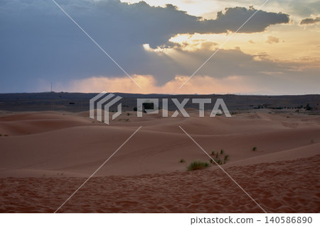 The setting sun disappears behind the majestic sand dunes of the Merzouga desert at sunset in Morocco The setting sun disappears behind the majestic sand dunes of the Merzouga desert at sunset in Morocco 140586890