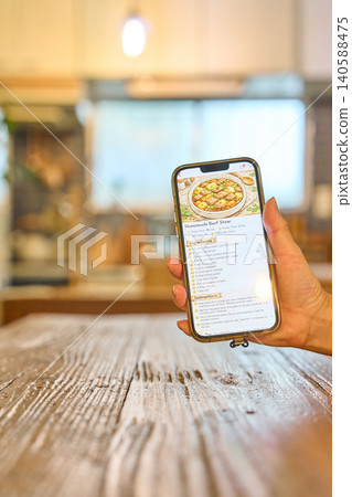 Looking at the recipe displayed on the smartphone Looking at the recipe displayed on the smartphone 140588475