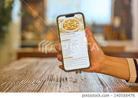 Looking at the recipe displayed on the smartphone Looking at the recipe displayed on the smartphone 140588476