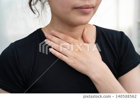Asian woman touching her neck and throat for thyroid gland problem. Asian woman touching her neck and throat for thyroid gland problem. 140588562