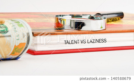 A book titled Talent vs Laziness sits on a table beside a rolled hundred dollar bill and a magnifying glass. The setup suggests a theme of evaluation and analysis A book titled Talent vs Laziness sits on a table beside a rolled hundred dollar bill and a magnifying glass. The setup suggests a theme of evaluation and analysis 140588679