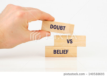 A hand holds a block that has the word doubt while other blocks with the word belief sit stacked below it. This shows the theme of choices and thoughts A hand holds a block that has the word doubt while other blocks with the word belief sit stacked below it. This shows the theme of choices and thoughts 140588693