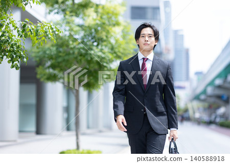 A man walking down the street in a suit A man walking down the street in a suit 140588918