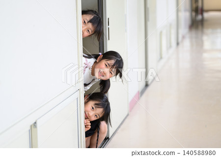 女孩們滿懷期待地從教室門口向外張望。 女孩們滿懷期待地從教室門口向外張望。 140588980