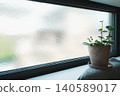 A windowsill with black window frames and patterned glass, featuring a natural interior with houseplants. 140589017