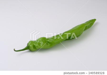 A green horn pepper, a vegetable with long, horn-shaped leaves, against a white background. A green horn pepper, a vegetable with long, horn-shaped leaves, against a white background. 140589328