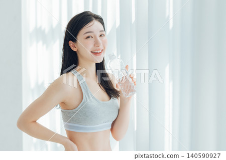 Woman drinking water by the window Woman drinking water by the window 140590927