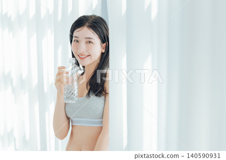 Woman drinking water by the window Woman drinking water by the window 140590931