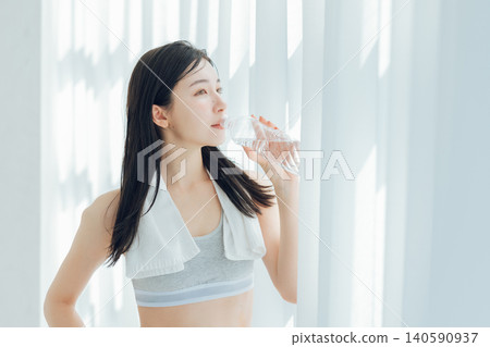 Woman drinking water by the window Woman drinking water by the window 140590937