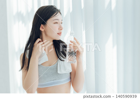 Woman drinking water by the window Woman drinking water by the window 140590939
