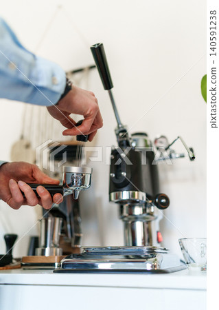 Man brewing espresso at home using a manual lever coffee machine. Man brewing espresso at home using a manual lever coffee machine. 140591238