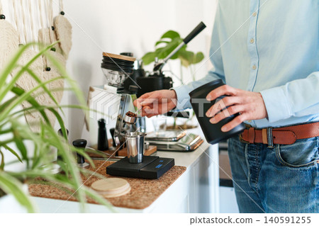 Man brewing espresso at home using a manual lever coffee machine. Man brewing espresso at home using a manual lever coffee machine. 140591255