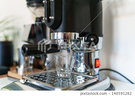 Home barista corner with a manual lever espresso machine and a single dose coffee grinder. 140591262