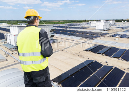 Technician managing large-scale solar power system on a commercial warehouse Technician managing large-scale solar power system on a commercial warehouse 140591322