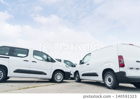 White delivery vans are parked in rows. Commercial fleet of vehicles. 140591323