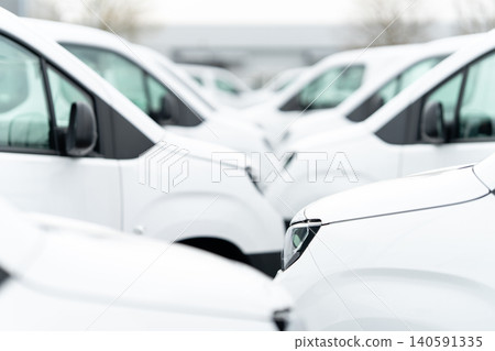 White delivery vans are parked in rows. Commercial fleet of vehicles 140591335