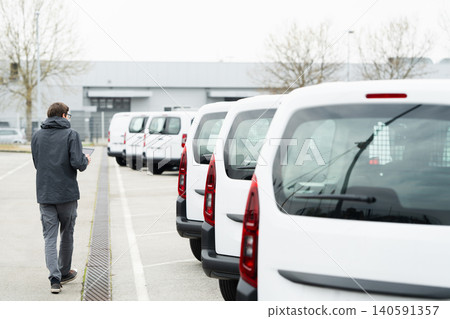 Fleet manager with digital tablet supervising rows of white delivery vans Fleet manager with digital tablet supervising rows of white delivery vans 140591357