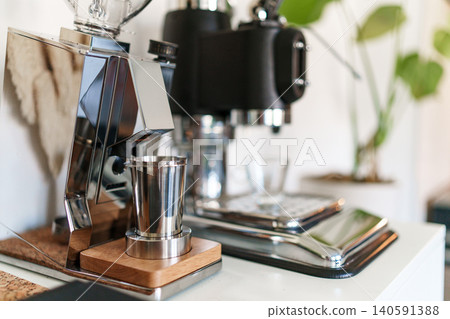 Home barista corner with a manual lever espresso machine and a single dose coffee grinder. 140591388