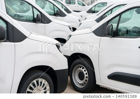 White delivery vans are parked in rows. Commercial fleet of vehicles 140591389