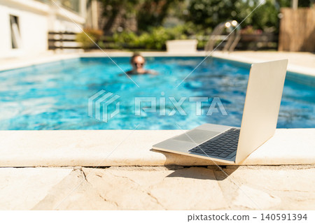 A woman trains in a swimming pool with a laptop. 140591394