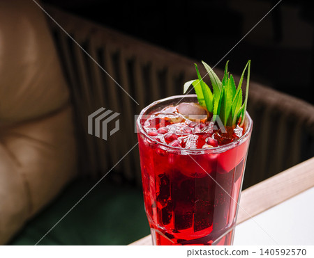 Refreshing pomegranate cocktail with ice and green garnish Refreshing pomegranate cocktail with ice and green garnish 140592570