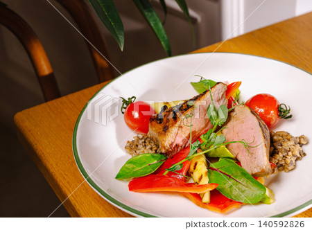 Grilled pork medallions with roasted vegetables and cherry tomatoes 140592826