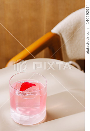 Pink cocktail with rose petal on light table Pink cocktail with rose petal on light table 140592954