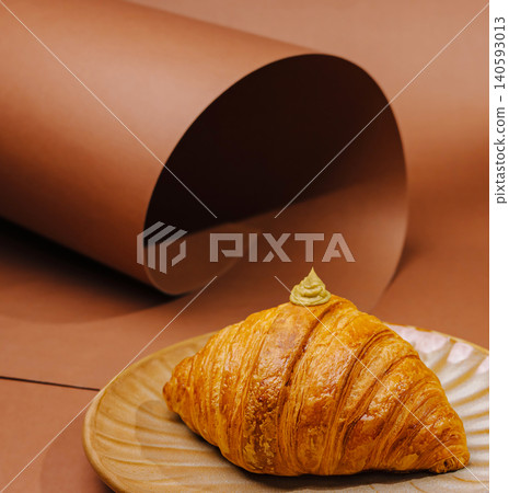 Fresh croissant with pistachio cream on plate 140593013
