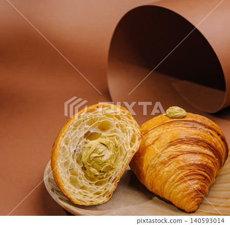Cut croissant with pistachio cream on plate 140593014