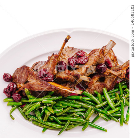 Lamb chops with green beans and cherries served on a white plate Lamb chops with green beans and cherries served on a white plate 140593102