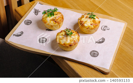 Freshly baked mini quiches with herbs on a wooden serving board Freshly baked mini quiches with herbs on a wooden serving board 140593133