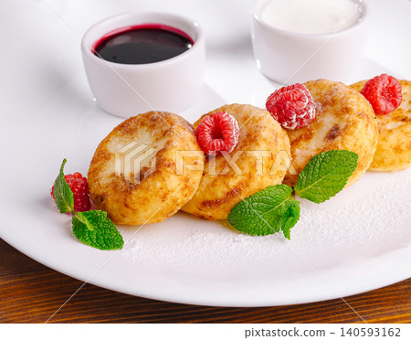 Golden cottage cheese pancakes with raspberries and mint leaves Golden cottage cheese pancakes with raspberries and mint leaves 140593162