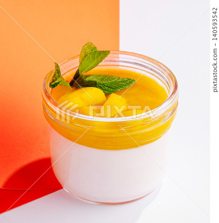 Pudding with mango topping and mint leaves in a jar on a colorful background Pudding with mango topping and mint leaves in a jar on a colorful background 140593542