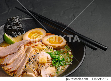 Delicious ramen dish served in a black bowl with toppings and chopsticks ready Delicious ramen dish served in a black bowl with toppings and chopsticks ready 140593587