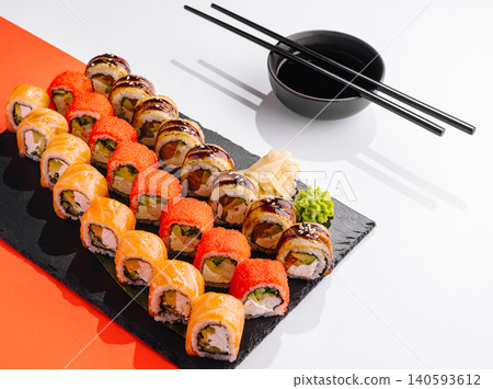 Fresh sushi rolls served on a black plate with chopsticks and a bowl Fresh sushi rolls served on a black plate with chopsticks and a bowl 140593612