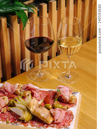Enjoying wine and cheese at a dining table with a charcuterie board Enjoying wine and cheese at a dining table with a charcuterie board 140593680