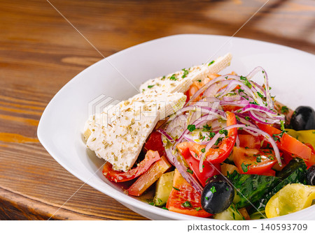 Fresh salad with vegetables and cheese served on a wooden table Fresh salad with vegetables and cheese served on a wooden table 140593709
