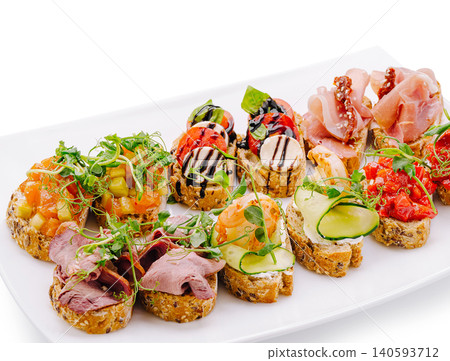 Different types of small bites on a white plate at a gathering Different types of small bites on a white plate at a gathering 140593712