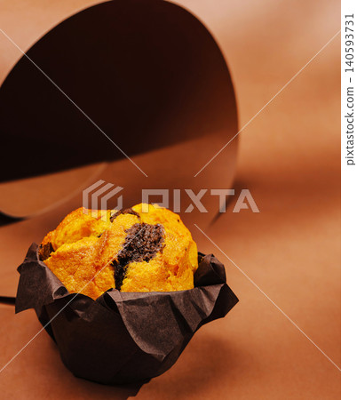 Freshly baked muffin on a brown surface with simple wrapping Freshly baked muffin on a brown surface with simple wrapping 140593731