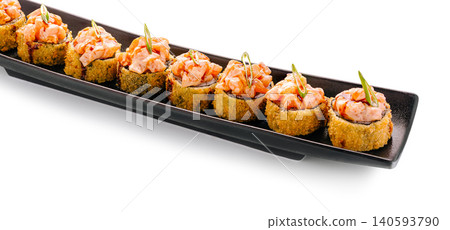 Sushi rolls with salmon and crispy coating on a long black plate Sushi rolls with salmon and crispy coating on a long black plate 140593790