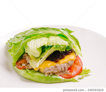 Healthy burger with lettuce wrap and vegetables served on a white plate Healthy burger with lettuce wrap and vegetables served on a white plate 140593828