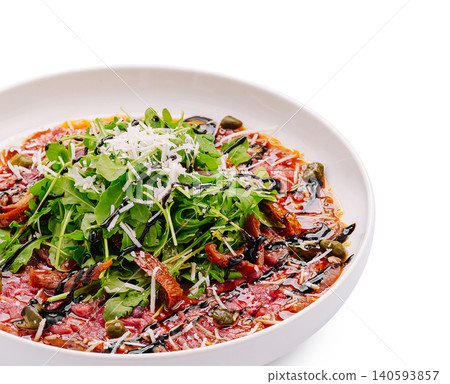 Beef carpaccio served in a white bowl with arugula and herbs Beef carpaccio served in a white bowl with arugula and herbs 140593857