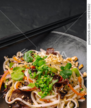 Noodles with vegetables and herbs served on a dark plate Noodles with vegetables and herbs served on a dark plate 140593882