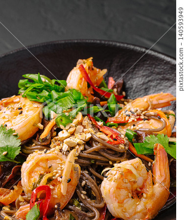 Shrimp and noodle dish served in a black bowl with colorful vegetables Shrimp and noodle dish served in a black bowl with colorful vegetables 140593949