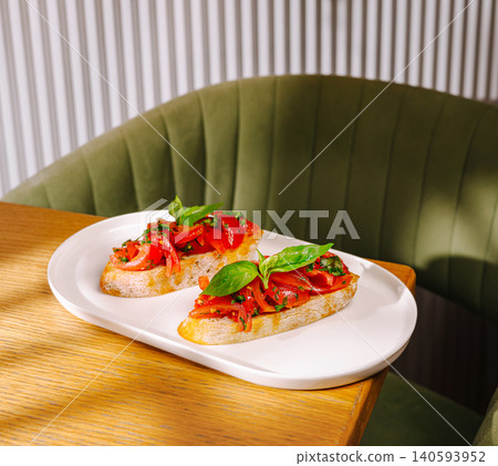 Fresh bruschetta served on a white plate at a cozy restaurant setting Fresh bruschetta served on a white plate at a cozy restaurant setting 140593952