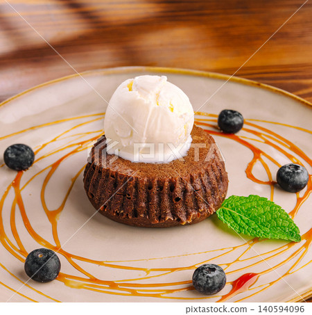 Delicious dessert with cake, ice cream, and berries served on a plate Delicious dessert with cake, ice cream, and berries served on a plate 140594096